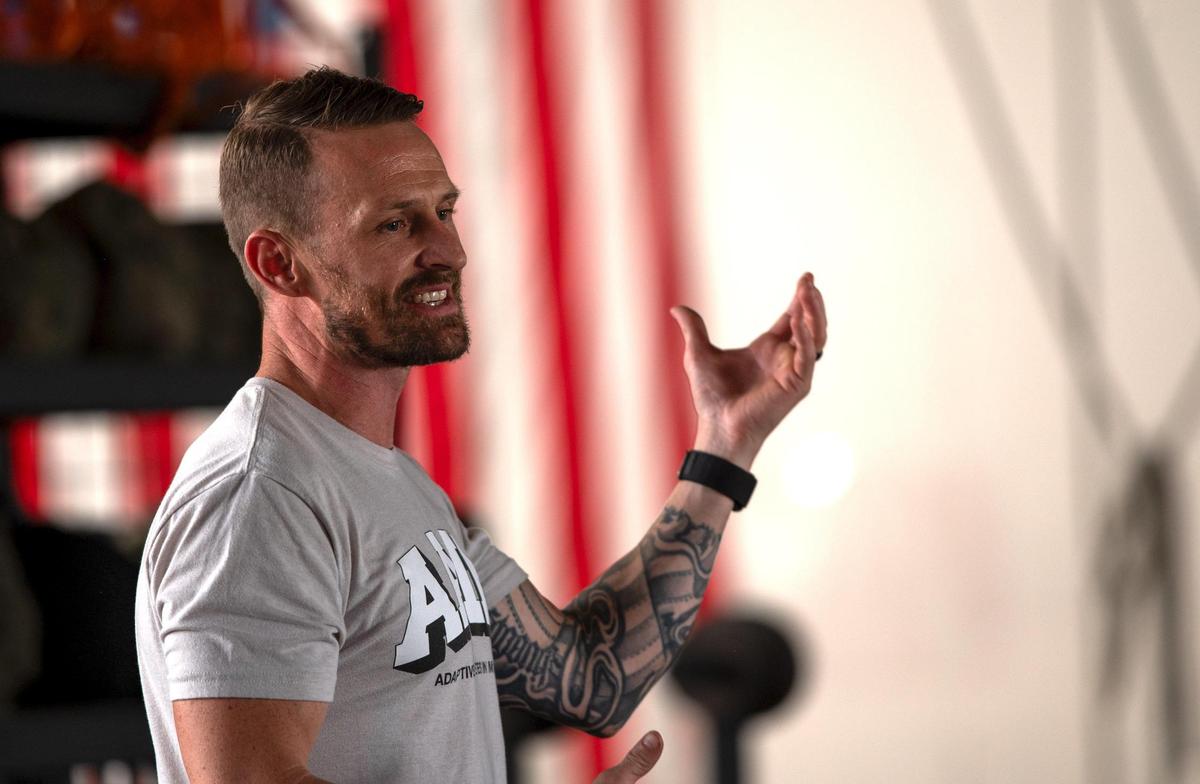 Josh Snyder, founder and head coach of Adaptive Athletes in Motion, speaks to a group of people during a fundraising event for the program at Brave Enough CrossFit in Kansas City. Snyder founded the Adaptive Athletes in Motion program because he wanted to train all athletes, not just athletes without disabilities, he said.