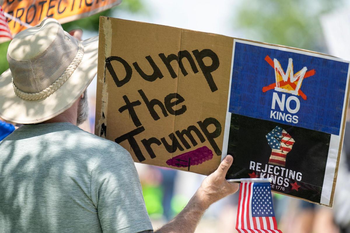 Protesters lined West 87th Street with signs as part of a nationwide “No Kings” day of defiance on Saturday, June 14, 2025, in Lenexa, Kansas. The events protest President Donald Trump and immigration policies, among other issues.