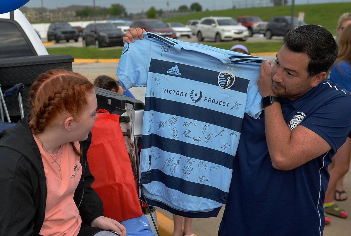 Dario Jaramillo, Brinley’s soccer coach holds up a jersey that is gifted to her, Monday, July 12, 2021 at California Trail Middle School in Olathe. This is the first time she has seen some friends, coaches and community members since having surgery.