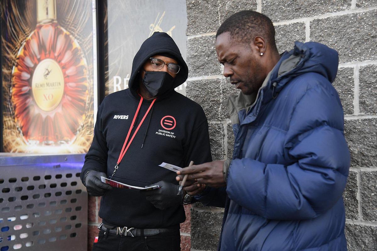 Berryman Rivers, lead community engagement specialist, provides mental health information to a resident during a street level outreach event in St. Louis. Missouri. The group sets up sites to offer services near areas where people are buying and using drugs.