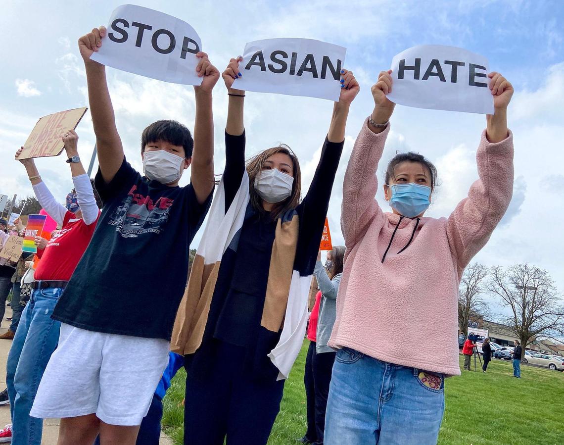 Xinbo Lyu of Greenwood, 12, his mom Yanyu Sun and Xue Cai of Shawnee held up a sequence of signs saying “Stop Asian Hate.” Mother and son met Cai at the rally when they needed someone to hold up the last sign. Nearly 150 people attended a rally at Highland Plaza on 119th Street in Overland Park Saturday, March 27, 2021, to bring attention to hate crimes committed against Asian people. A newly formed group, Allies Against Asian Hate, organized the event.