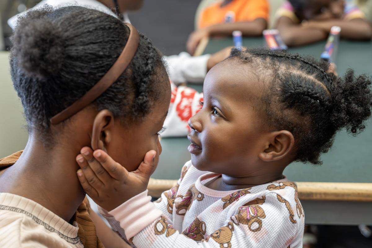 Lauren Henderson, left, has her face cradled by her sister Peace while playing on Tuesday, Aug. 19, 2025, in Kansas City.