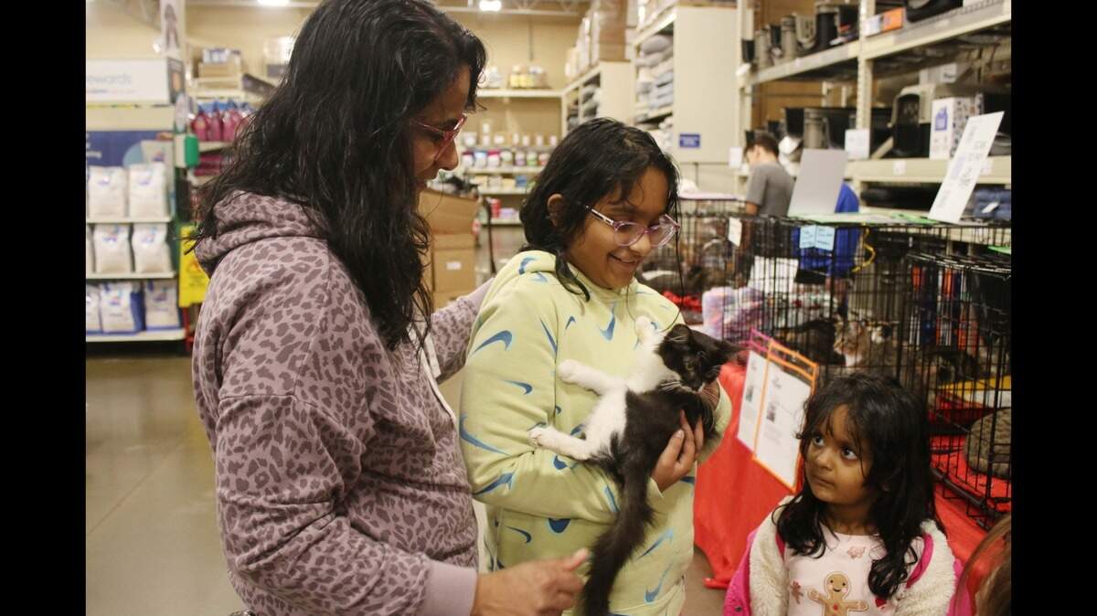 Sruthy Vijay, Gowri Panicker, 11, and Thanvi Panicker, 4, get to know a cat named Whittaker during a Cat’s Pawjamas event at PetSmart in Olathe.