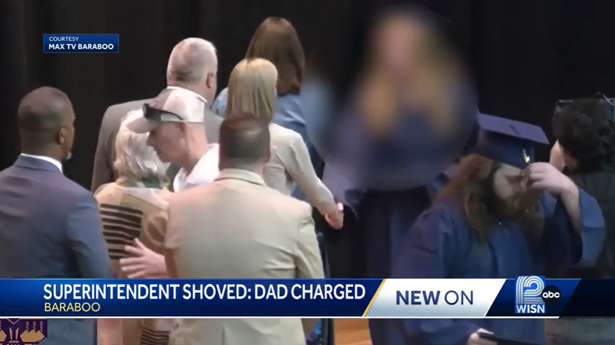 A viral video shows a man pushing a school superintendent as his daughter walks across the stage at a Wisconsin graduation. He’s charged.