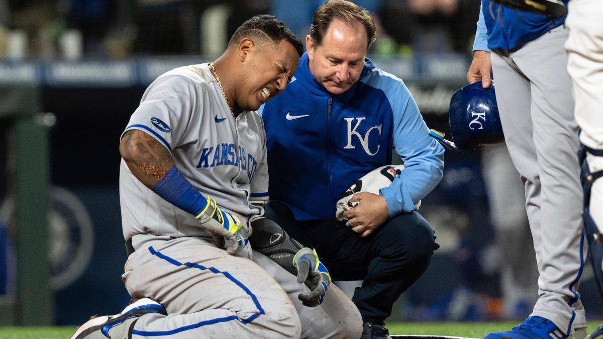 Kansas City Royals’ Salvador Perez grimaces next to a trainer after being hit by a pitch during the seventh inning of the team’s baseball game against the Seattle Mariners, Saturday, April 23, 2022, in Seattle. (AP Photo/Stephen Brashear)