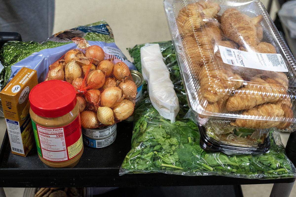 Food including leafy greens, boxed macaroni and cheese, potatoes and peanut butter sits on a cart at the Redemptorist Center on Monday, Nov. 3, 2025, in Kansas City. Food pantries across the region are struggling to meet demand as many families face reduced or frozen SNAP benefits.
