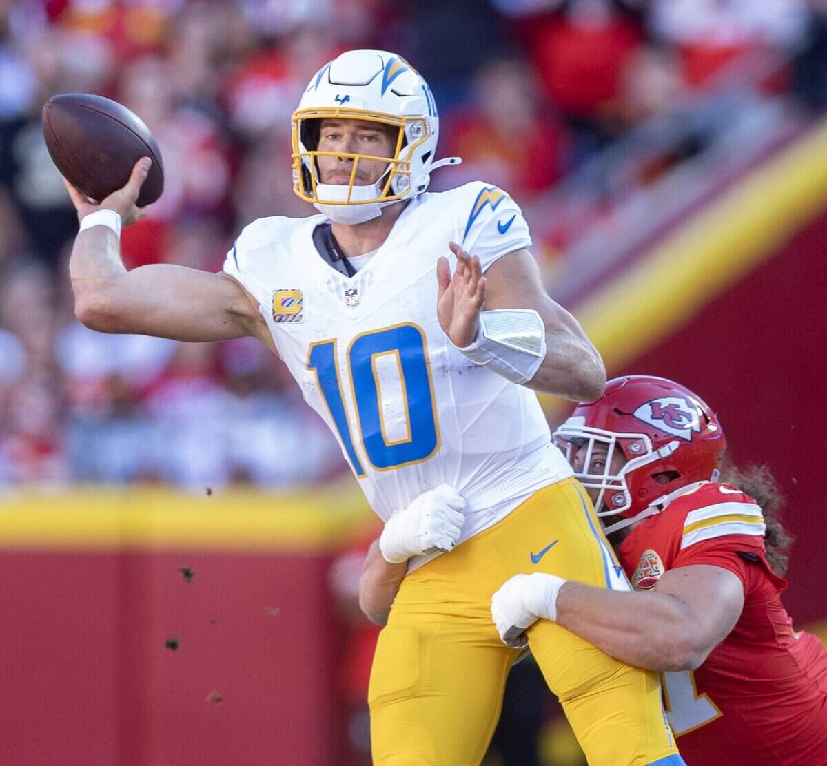 Los Angeles Chargers quarterback Justin Herbert (10) is pressured into throwing an interception after getting pressure from Kansas City Chiefs defensive end Ashton Gillotte (97) during the first half on Sunday at Arrowhead Stadium.