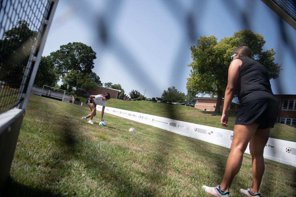Before taking a penalty kick, blind soccer players lean down to touch the ball and confirm its position. Leah Enright, Kansas State School for the Blind’s blind sports coordinator, taught KC Star intern Kylie Volavongsa a few blind soccer basics, including how to take penalty kicks, at KSSB’s blind soccer field on Thursday, August 1, 2024, in Kansas City, Kansas.