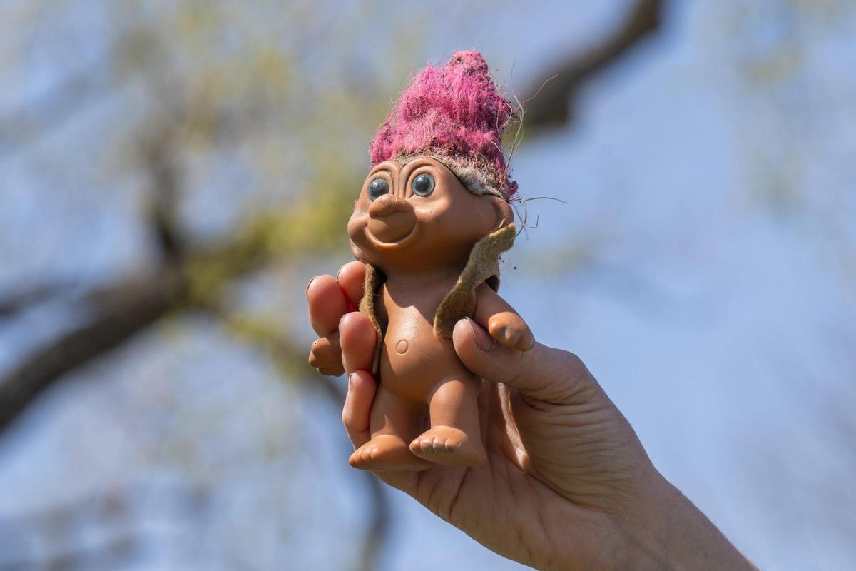 A troll doll found along the riverbank is held up during Saturday’s cleanup event.