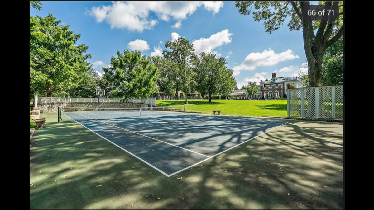 The backyard at 1228 W. 56th St. in Kansas City has a private tennis court, with one side of the court having a basketball hoop.