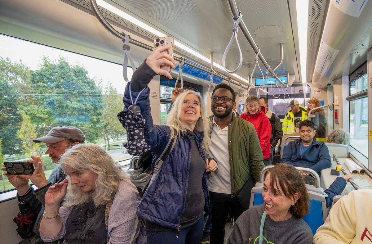 Kyla McAuliffe of San Jose, California, and Joshua Koni of Kansas City, both former students at the University of Missouri-Kansas City, take a selfie as they ride the KC Streetcar during an inaugural run during the grand opening celebration Friday, October 24, 2025, in Kansas City. The extension for the KC Streetcar added a stop on the Plaza and at the UMKC campus.