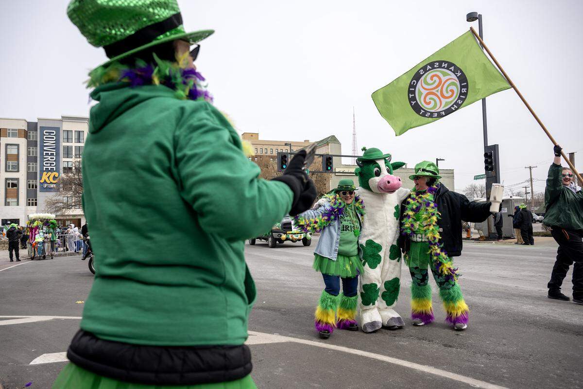 Tiffany Thompson, left, and Sherry Haddock greet a cow mascot during the St. Patrick's Day parade along Broadway Boulevard on Tuesday, March 17, 2026, in Kansas City.