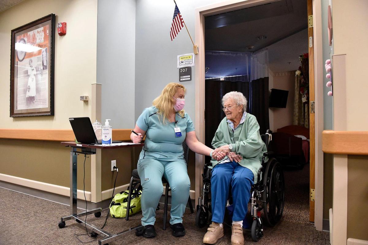 Grace Moody came out of her room to visit Brenda Newell, a certified medication aid who was stationed outside Moody’s door, and they hold hands as they talk Friday, July 30, 2021. Newell, with the skilled nursing facility Good Samaritan Society - Olathe, and Moody, who recently turned 106 1/2, are both vaccinated against COVID-19. Good Samaritan is mandating that all employees be vaccinated beginning Nov. 1.