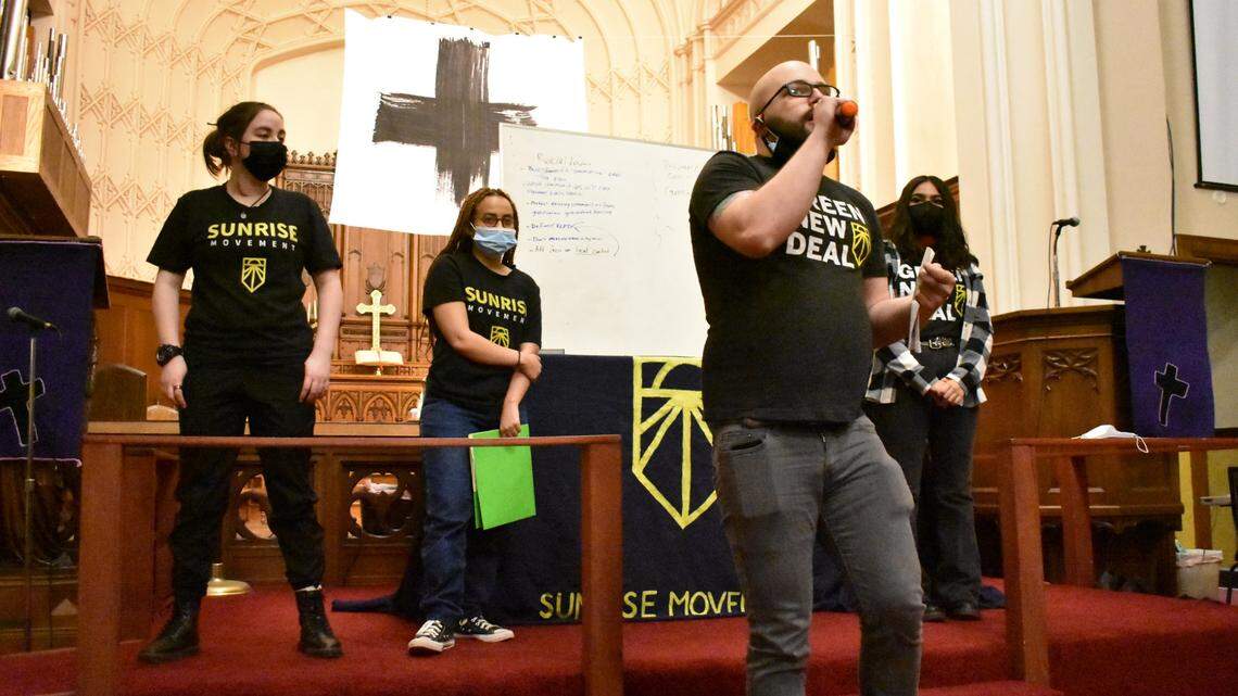 Michael Wolfe, center, speaks onstage at the People’s Climate Town Hall on Wednesday, April 6 alongside other members of the Kansas City chapter of the Sunrise Movement.