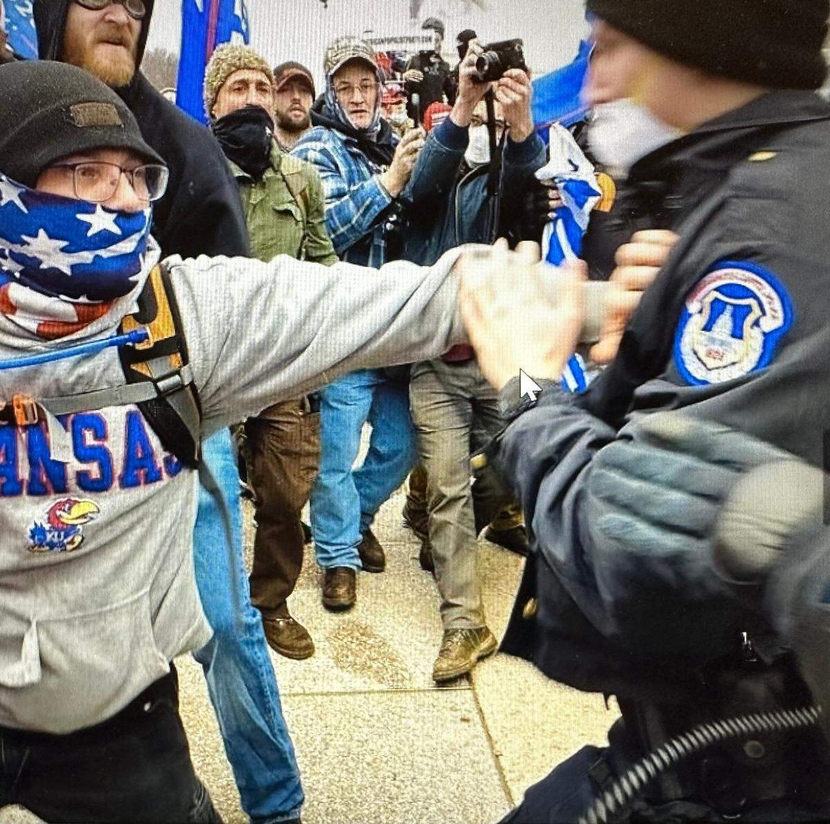 Prosecutors say Christopher Roe, left, shoves a U.S. Capitol Police officer during an altercation outside the Capitol on Jan. 6, 2021.