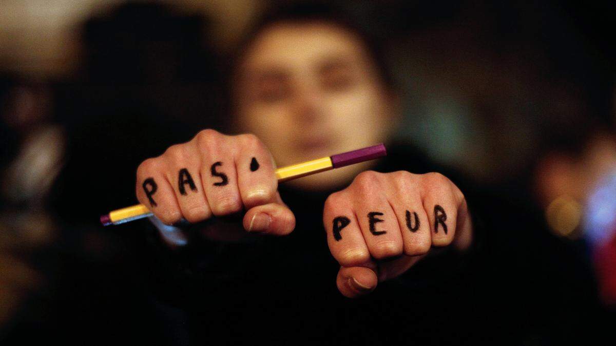 A woman holds up her hands bearing the words "Not afraid" in French during a gathering in solidarity of the victims of a terror attack against French satirical newspaper Charlie Hebdo in Paris, Wednesday, Jan. 7, 2015. Masked gunmen stormed the Paris offices of a weekly newspaper that caricatured the Prophet Muhammad, methodically killing 12 people Wednesday, including the editor, before escaping in a car. It was France's deadliest postwar terrorist attack. 