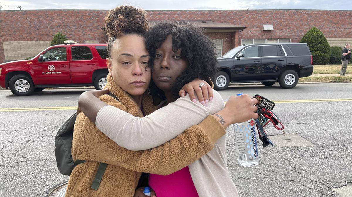Janay Douglas, left, and Renada Bridgett, right, hug outside of Central Visual and Performing Arts High School in St. Louis. Douglas’ 15-year-old was stuck in a hallway when the school shutdown during a shooting. Bridgett is the student’s aunt.
