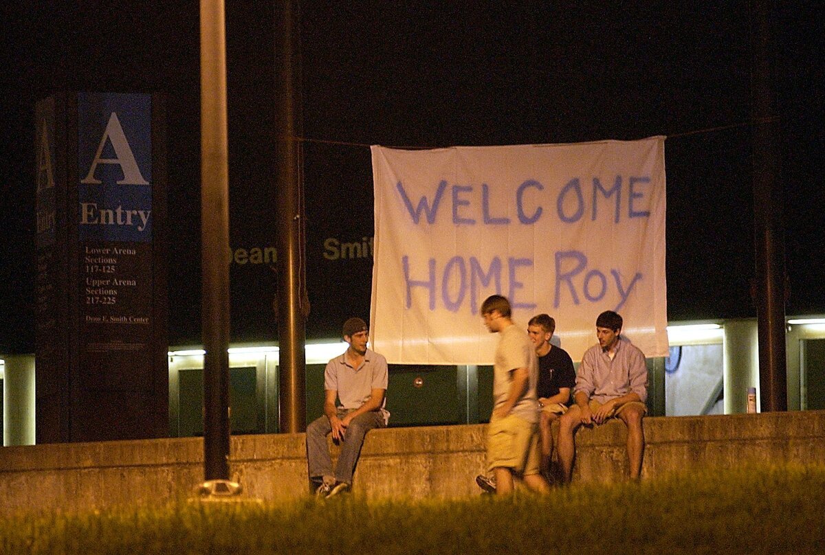 UNC students sit under a sign in front of the Dean Smith Center on Monday night, welcoming Roy Williams as the new coach of UNC in 2003.