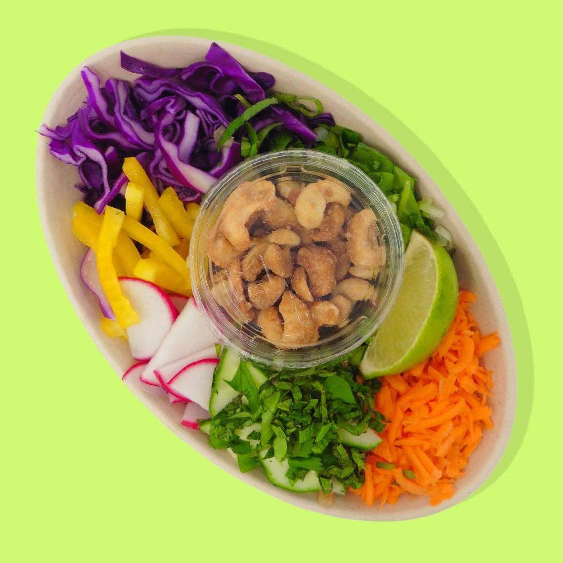 Canihaveabite’s Global Bowl with rice noodles cooked in a ginger-almond sauce and veggie broth, and topped with cabbage, carrots, sweet peppers, cucumbers, scallions, radishes, basil, cilantro, lime wedge and honey roasted cashews.