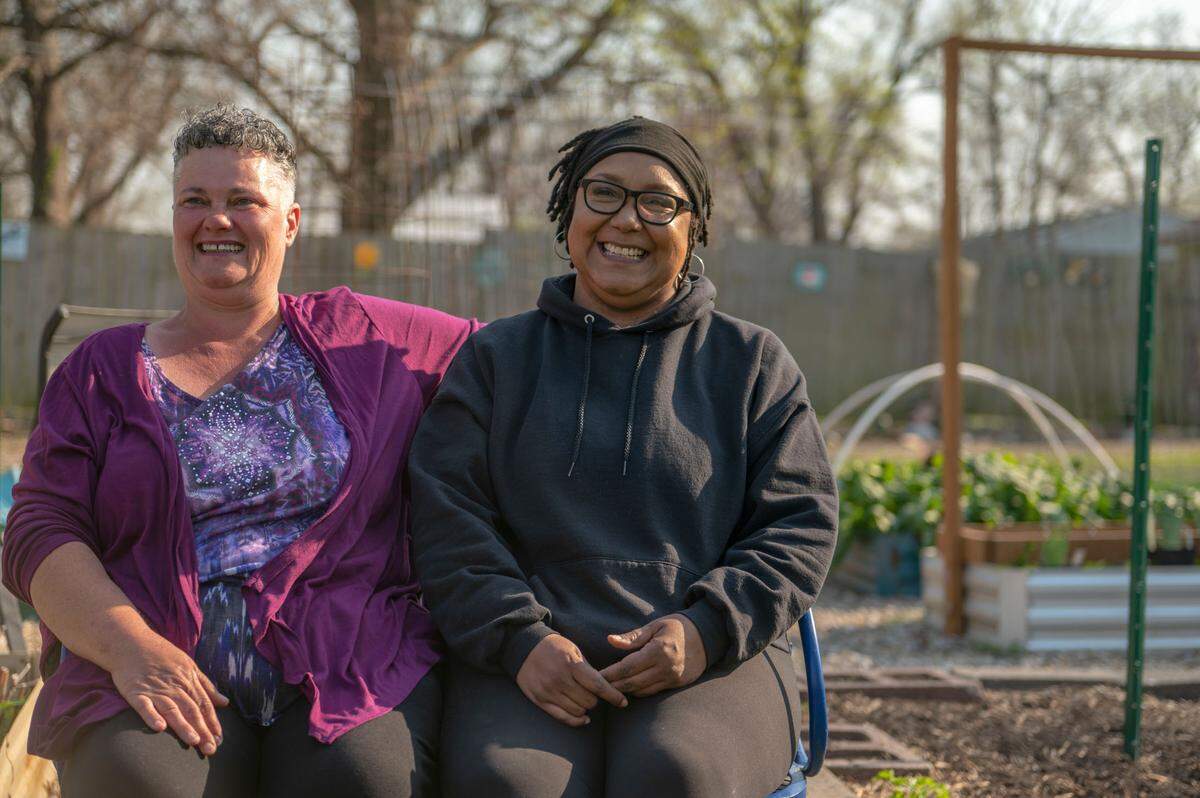 Heather Gray-Johnson, left, and Keisha Mitchell sit together in Gray-Johnson’s vegetable garden in Kansas City. They are avid home gardeners and members of the Kansas City Area Gardening Group.