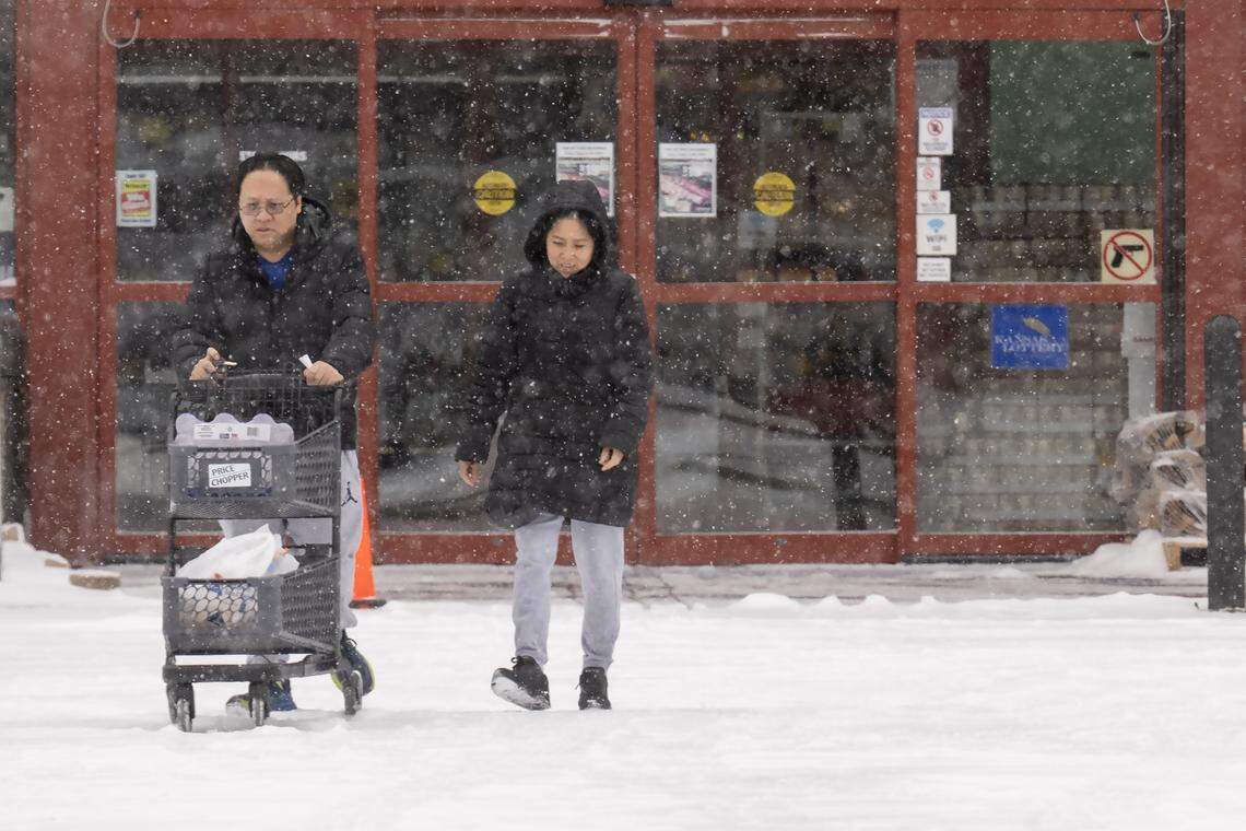 Shoppers head to a vehicle in bitter cold during a winter storm Saturday, Jan. 24 2026, in Lenexa, Kansas.