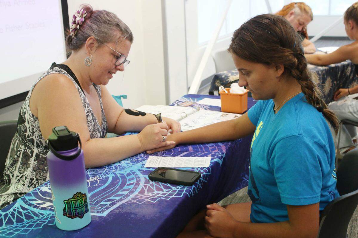 Thirteen-year-old Alice Hicks of Lee’s Summit gets a henna tattoo from Amanda DeLapp of Shadowlight Henna during a program at the Lee’s Summit branch of the Mid-Continent Public Library.