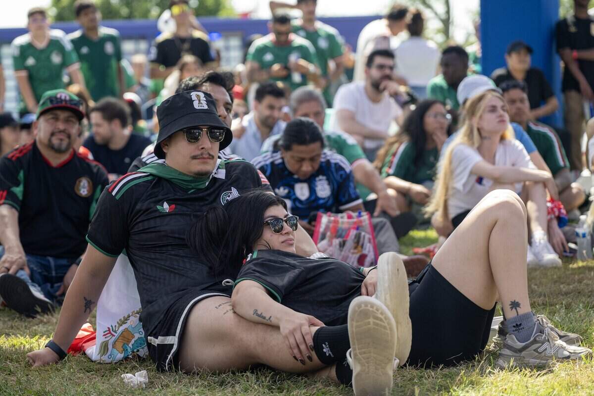 Mexico fans Daniel Moreno, left, and Valentina Gutierrez lounge on the grass while watching a FIFA World Cup match between Mexico and South Africa under the live plus canopy at the FIFA Fan Festival on Thursday, June 11, 2026, in Kansas City.