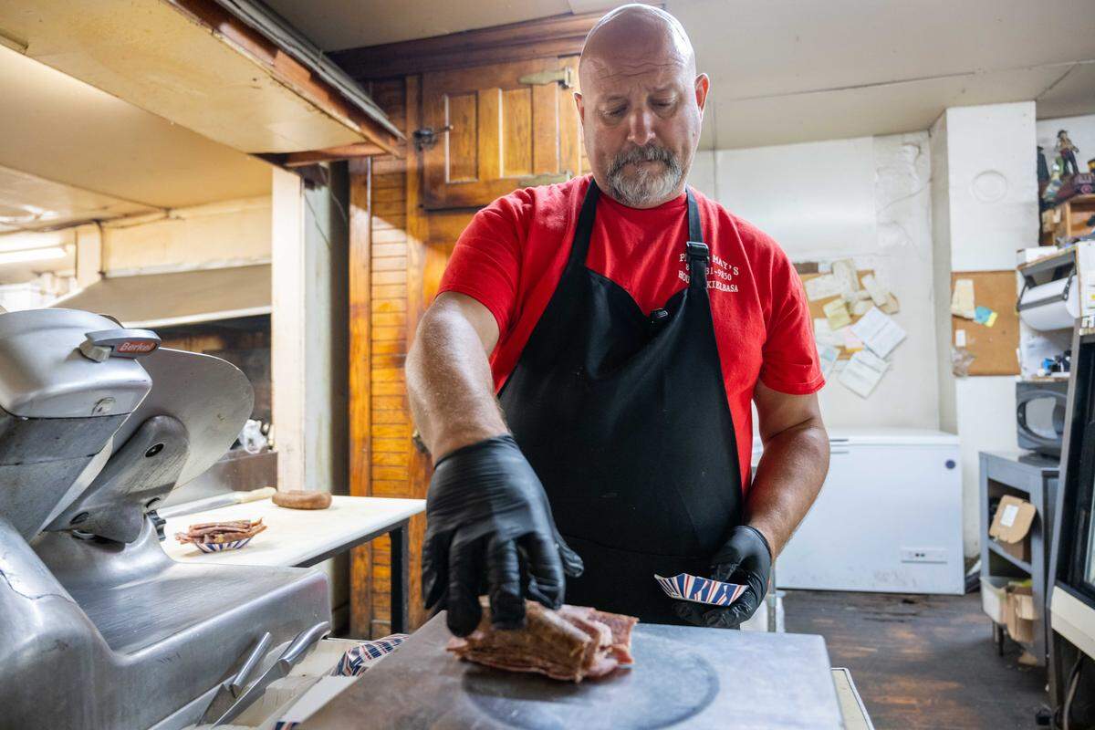 Mike Loges, owner of Peter May's House of Kielbasa, weighs cut sausages on a scale for an order, on Tuesday, Oct. 7, 2025. The hole-in-a-wall restaurant has been around since the 1940s and used to be a neighborhood grocery store.
