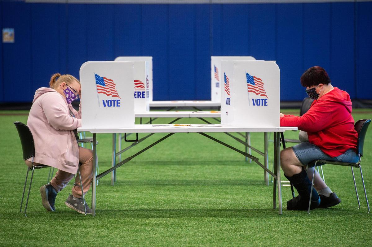 Shannon Davidson, 46, left, and Evelyn VanHeest, 50, right, vote on their paper ballots at the Kansas City Urban Youth Academy on Tuesday. “I feel very safe to come out and vote,” Davidson said.
