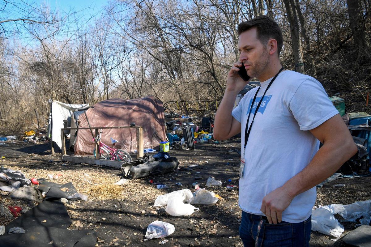 Josh Henges, Houseless Prevention Coordinator for Kansas City, takes a phone call about an encampment with 20 people living in it as he walks through another encampment on Wednesday, March 2, 2022, in an area near Independence Avenue. Henges was conducting a count of sheltered and unsheltered people experiencing houselessness.