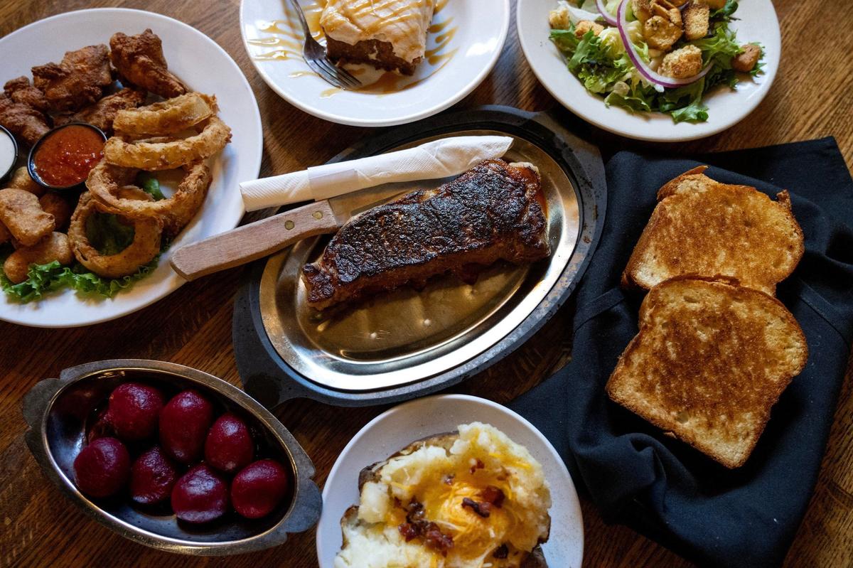 A variety of dishes, including pickled beets, house salad, garlic bread, appetizers, and a strip steak are served at Jess & Jim’s Steakhouse in Kansas City.