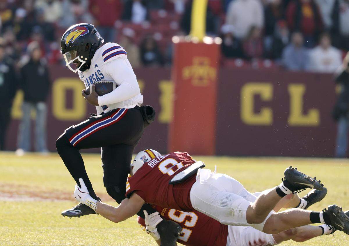 Jalon Daniels #6 of the Kansas Jayhawks is tackled by Drew Surges #29 and Vontroy Malone #8 of the Iowa State Cyclones as he scrambles for yards in the first half at Jack Trice Stadium on November 22, 2025, in Ames, Iowa.