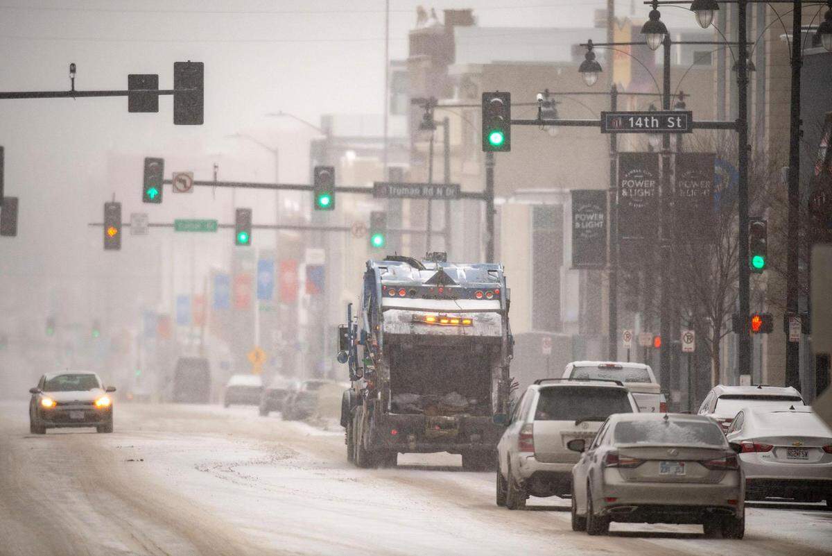 A Republic Services solid waste collection truck navigates along a snowy Grand Boulevard amid light snow and frigid temperatures on Monday, Jan. 15, 2024, in Kansas City.
