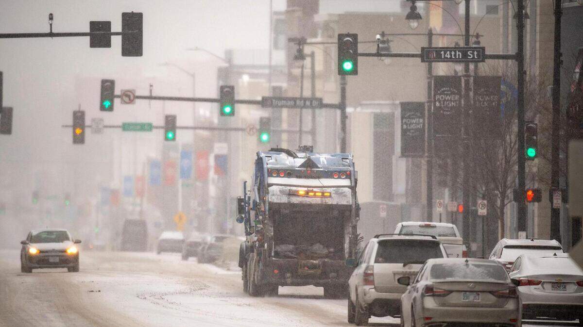 A Republic Services solid waste collection truck navigates along a snowy Grand Boulevard amid light snow and frigid temperatures on Monday, Jan. 15, 2024, in Kansas City.