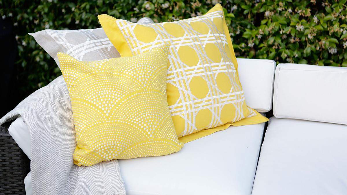 a white cushion cover and yellow pillows.