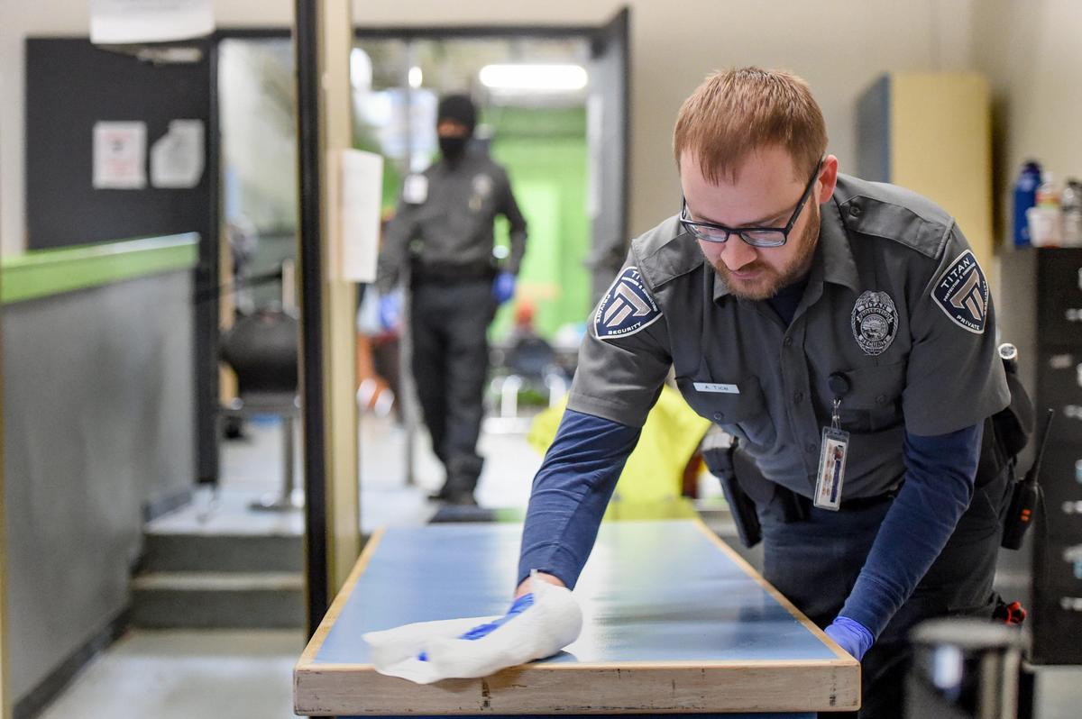 Ashley Tice of Titan Protection and Security wipes down the entry and screening area at Home Faith.