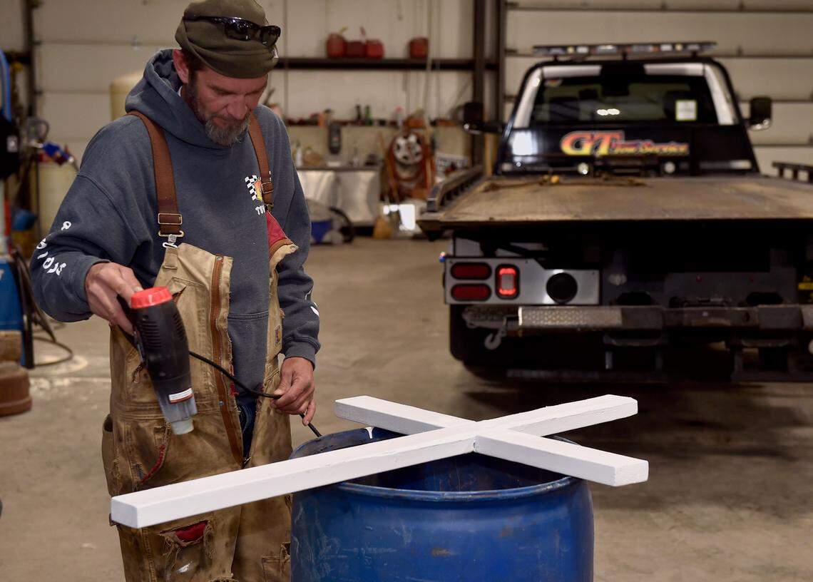 Jason Cockrum dried paint on a cross he was helping make for his friend and coworker John Stewart, who was struck and killed late Sunday while retrieving a vehicle on Interstate 35 in the Northland. Cockrum was at GT Tow Service in Smithville, where both men worked.