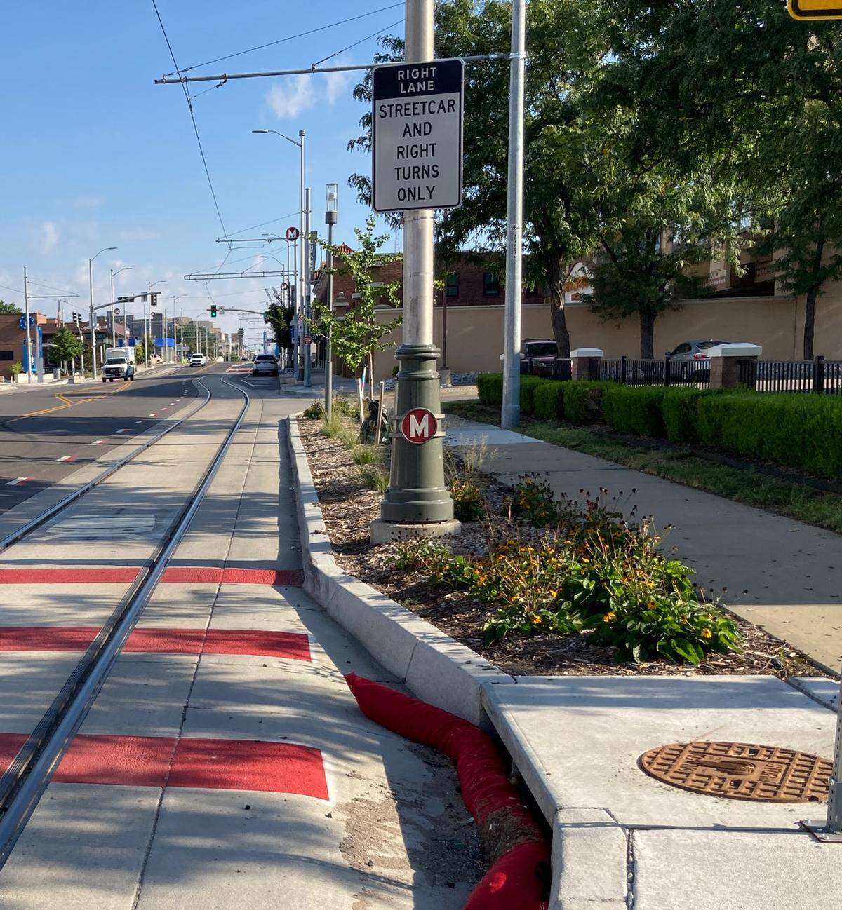 A street sign clearly tells motorists that the right lane is only for streetcars or buses or for cars that are wishing to turn right. Also seen are red “piano keys” indicating this is a transition zone.