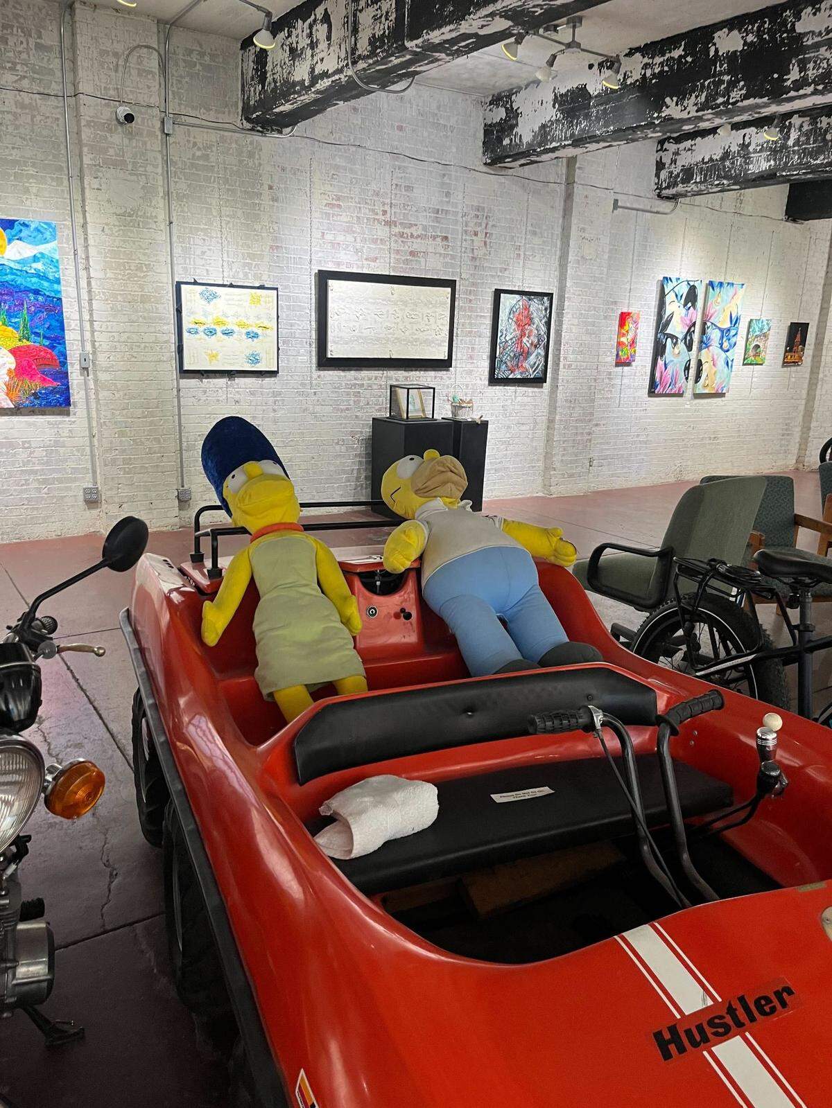 A display piece in the upstairs section at the Jones Galley features plush figures of Homer and Marge Simpson sitting inside a vehicle. Artwork surrounding the display ranged from $100 to $1,000.