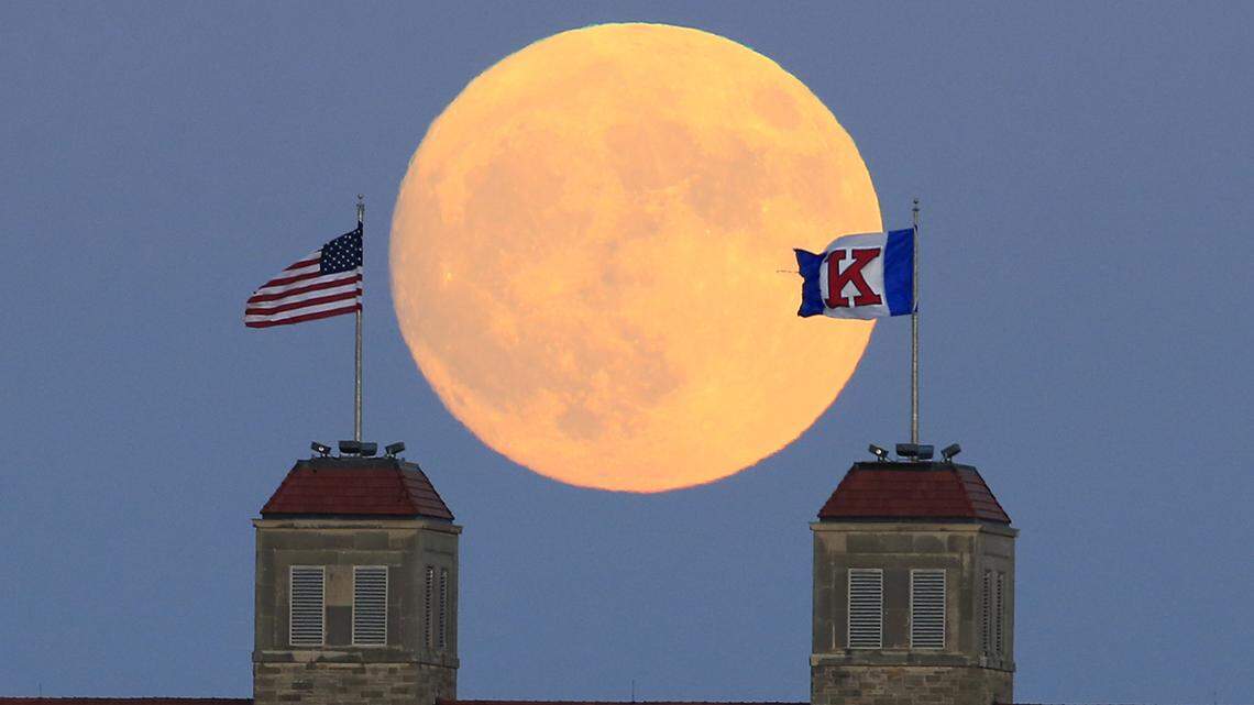 The moon rises beyond flags atop Fraser Hall on the University of Kansas campus in Lawrence, Kan., Sunday, Nov. 13, 2016. (AP Photo/Orlin Wagner)