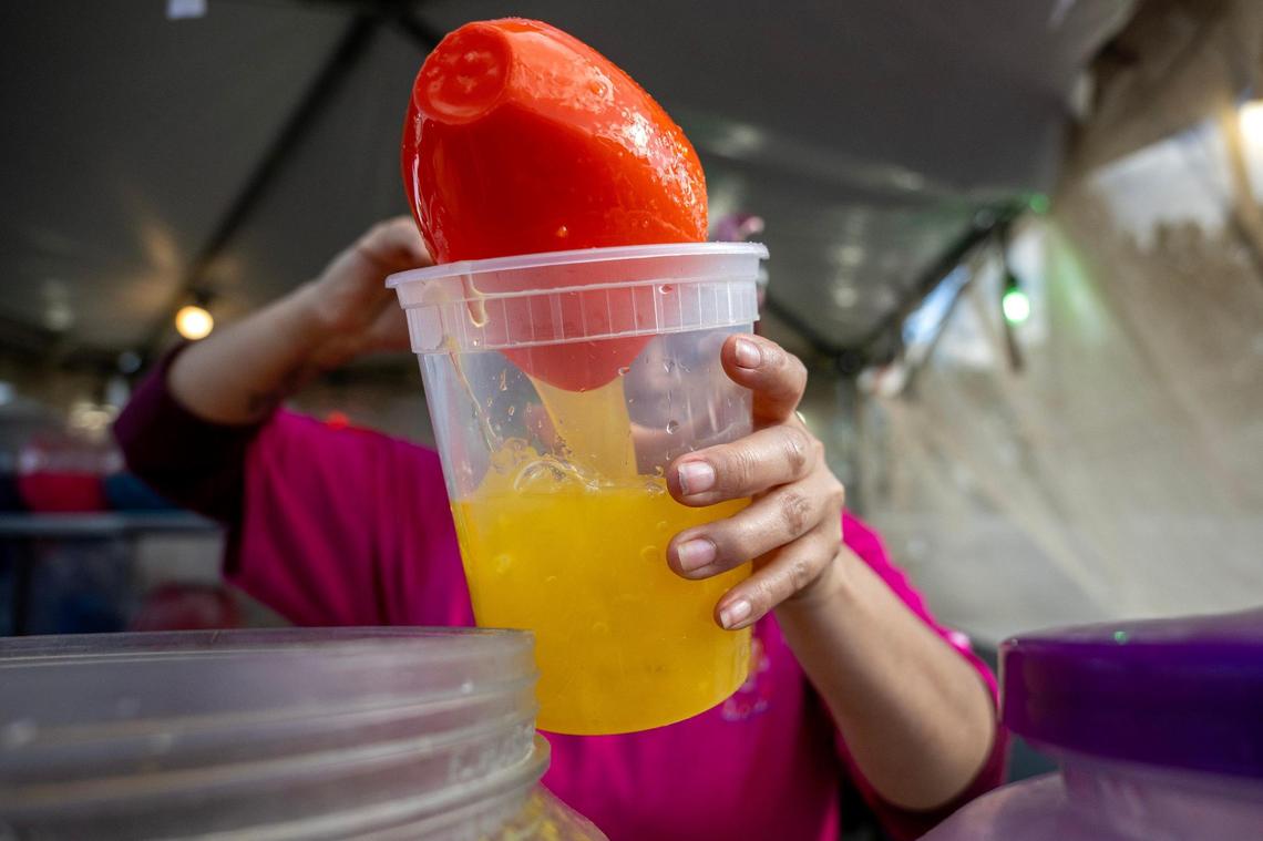 An employee of Frutas El Peloncin pours mango juice into a container for a customer during the Cinco de Mayo Festival.