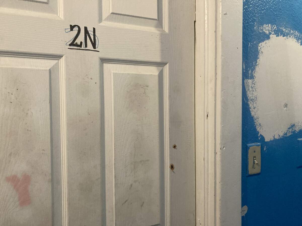 Bullet holes pierce the door of the upstairs apartment at East 12th Street and Askew Avenue where one man was killed Monday night, June 1, 2026, and his son was seriously injured.