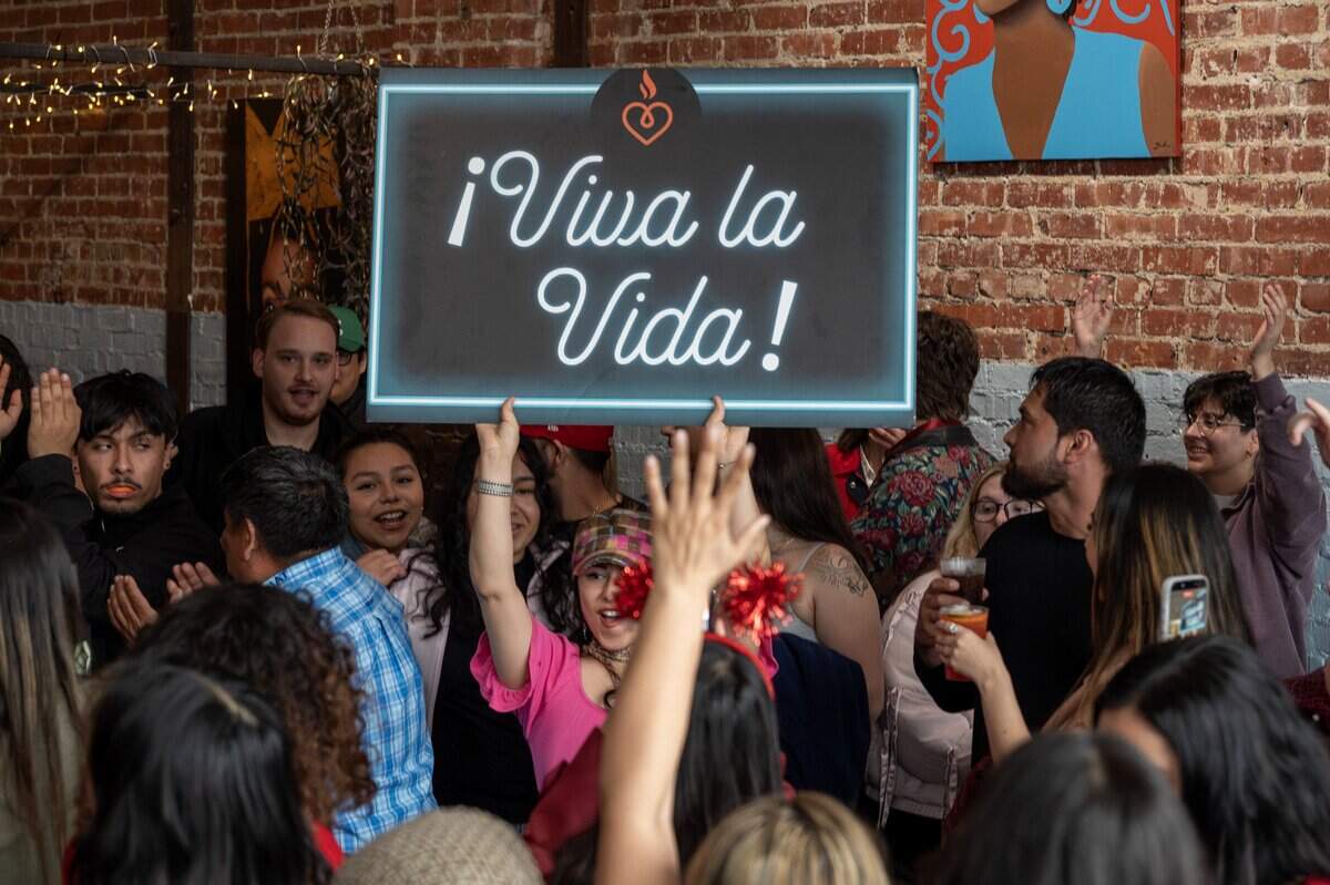 Attendees form a conga line behind a sign reading “Viva La Vida” during the Bad Bunny look-alike contest at Café Corazón on Saturday, Feb. 14, 2026, in Kansas City.