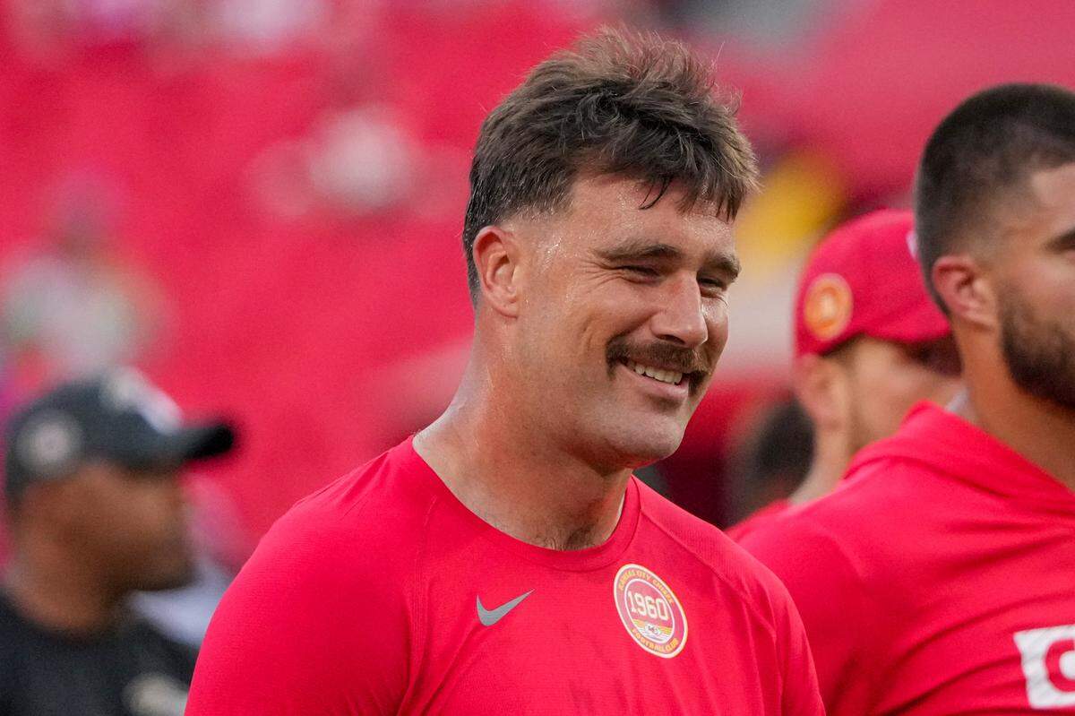 Kansas City Chiefs tight end Travis Kelce (87) laughs with teammates against the Baltimore Ravens during warm ups at GEHA Field at Arrowhead Stadium.