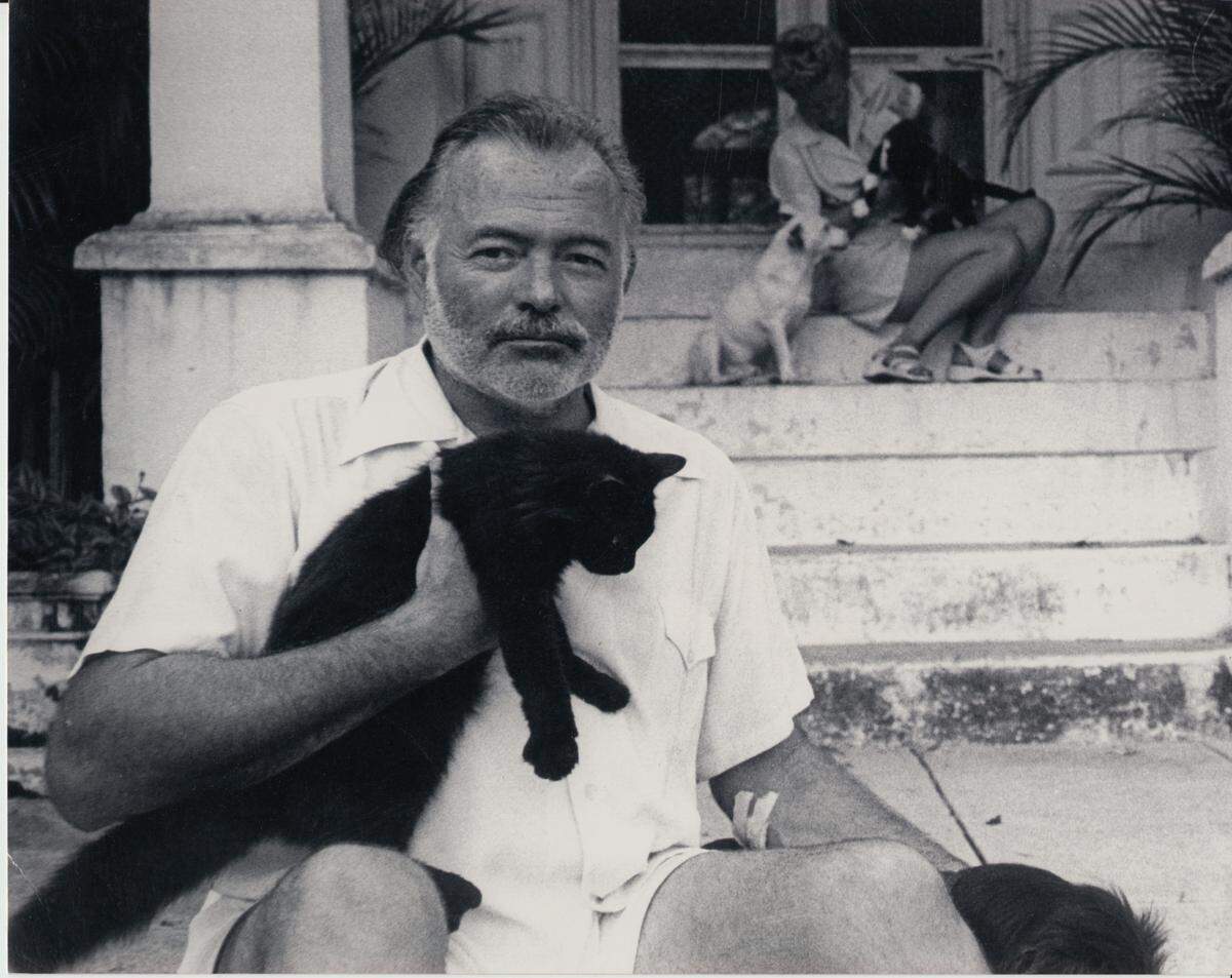 Ernest Hemingway at Finca Vigia, his home in Cuba in the 1950s. Behind him on the steps is his fourth wife, Mary, who would become his widow.