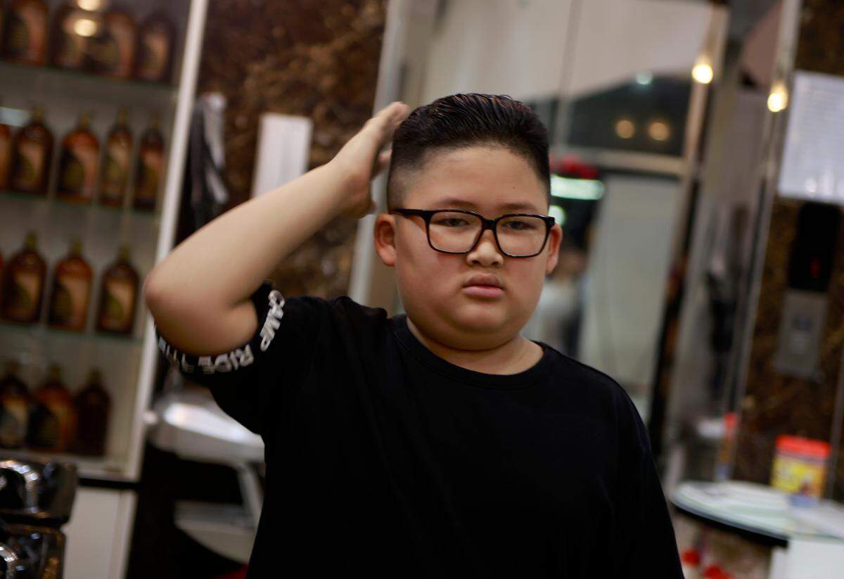 To Gia Huy, 9, checks his hair after having a Kim haircut in Hanoi, Vietnam.