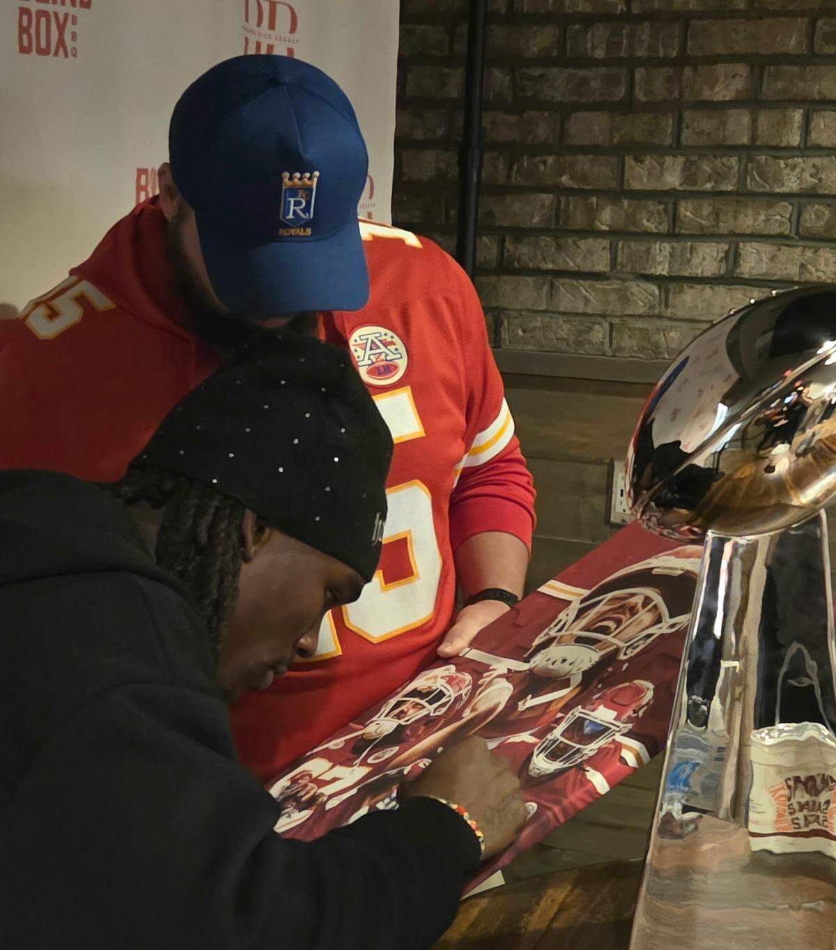 Rashee Rice autographs a jersey for a fan at Blind Box BBQ in Shawnee on Thursday.