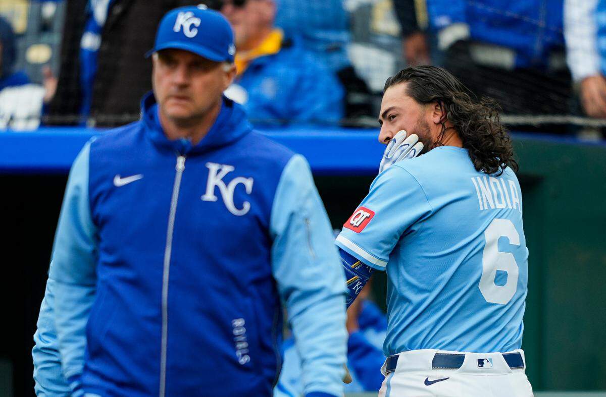 With manager Matt Quatraro at left in the foreground, Kansas City Royals left fielder Jonathan India holds his face after getting hit in the batting helmet by an Emmanuel Clase pitch in the ninth inning of a game against the Cleveland Guardians at Kauffman Stadium on Sunday, March 30, 2025.