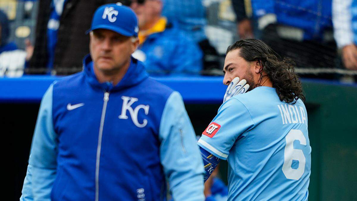 With manager Matt Quatraro at left in the foreground, Kansas City Royals left fielder Jonathan India holds his face after getting hit in the batting helmet by an Emmanuel Clase pitch in the ninth inning of a game against the Cleveland Guardians at Kauffman Stadium on Sunday, March 30, 2025.
