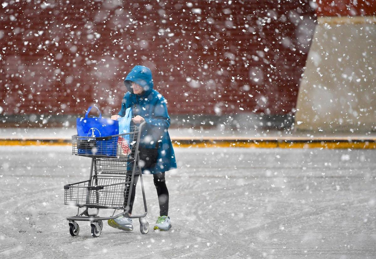 Snow fell as a shopper headed to the parking lot of a grocery store in Shawnee, Kansas, on Monday, Jan. 8, 2024.